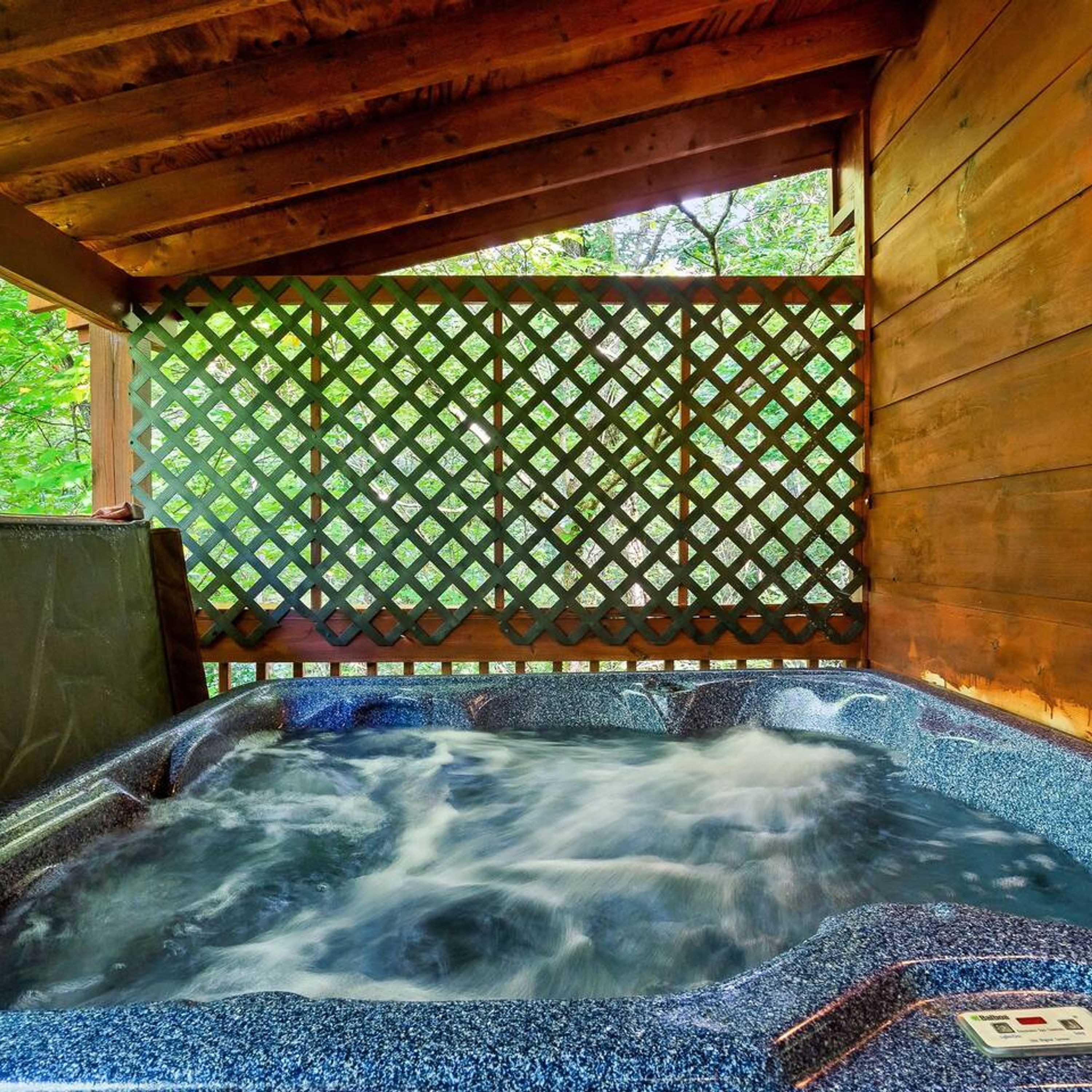 A hot tub with a wooden structure and a lattice fence.