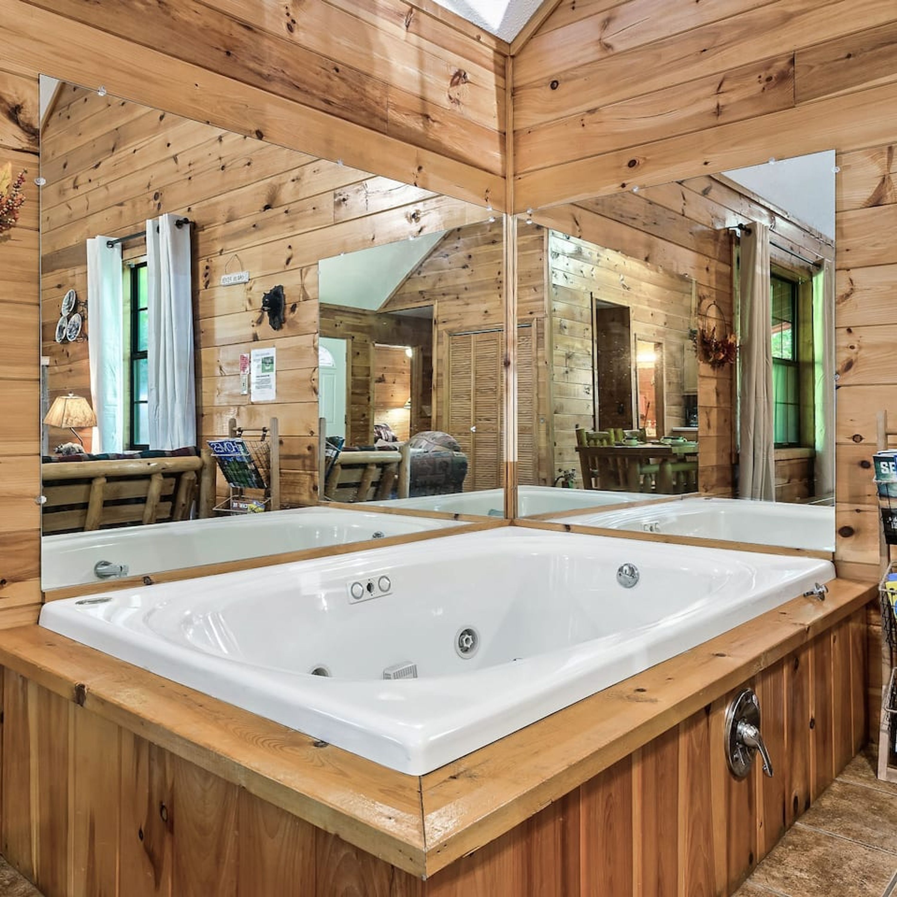 Una cabaña de madera con una bañera grande y blanca en el centro, rodeada de paredes de madera y un techo con espejos.