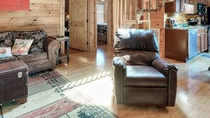 Un intérieur de chalet en bois spacieux, comprenant une chambre en mezzanine, un coin salon confortable et une cuisine.
