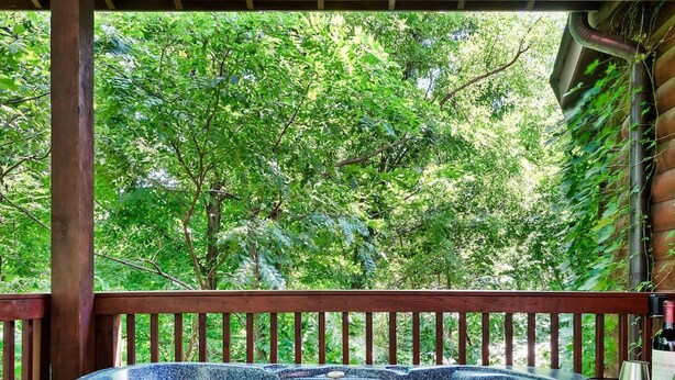 Un bain à remous avec une terrasse en bois et une vue sur une végétation luxuriante.