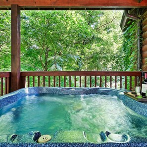 A hot tub with a wooden deck and a view of lush greenery. - Yurt I Game Room Hot Tub I Sleeps 8 I 2BR 2BA (Sevierville)