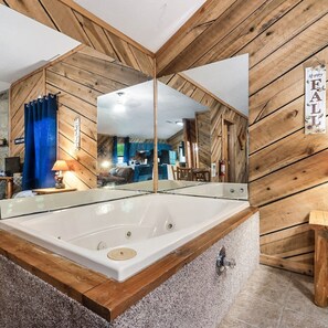 A modern bathroom with a large mirror, wooden walls, and a bathtub.