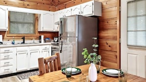 A wooden cabin interior with a kitchen, dining area, and a large window. - Views I Firepit I Pool Table I Hot Tub I Sleeps 4 (Sevierville)