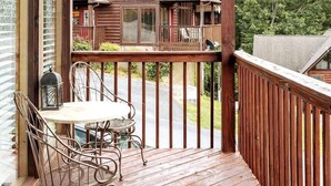 Une terrasse en bois avec une table et des chaises, donnant sur un chalet doté d’un porche et d’un garage.