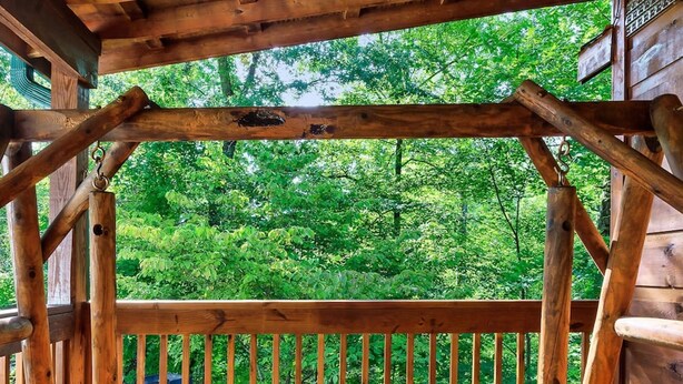 Una terraza de madera con un banco y vistas a un bosque.