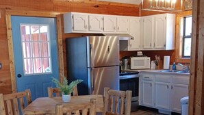 Un interior de madera con una mesa de comedor, sillas, un refrigerador, un microondas y armarios.