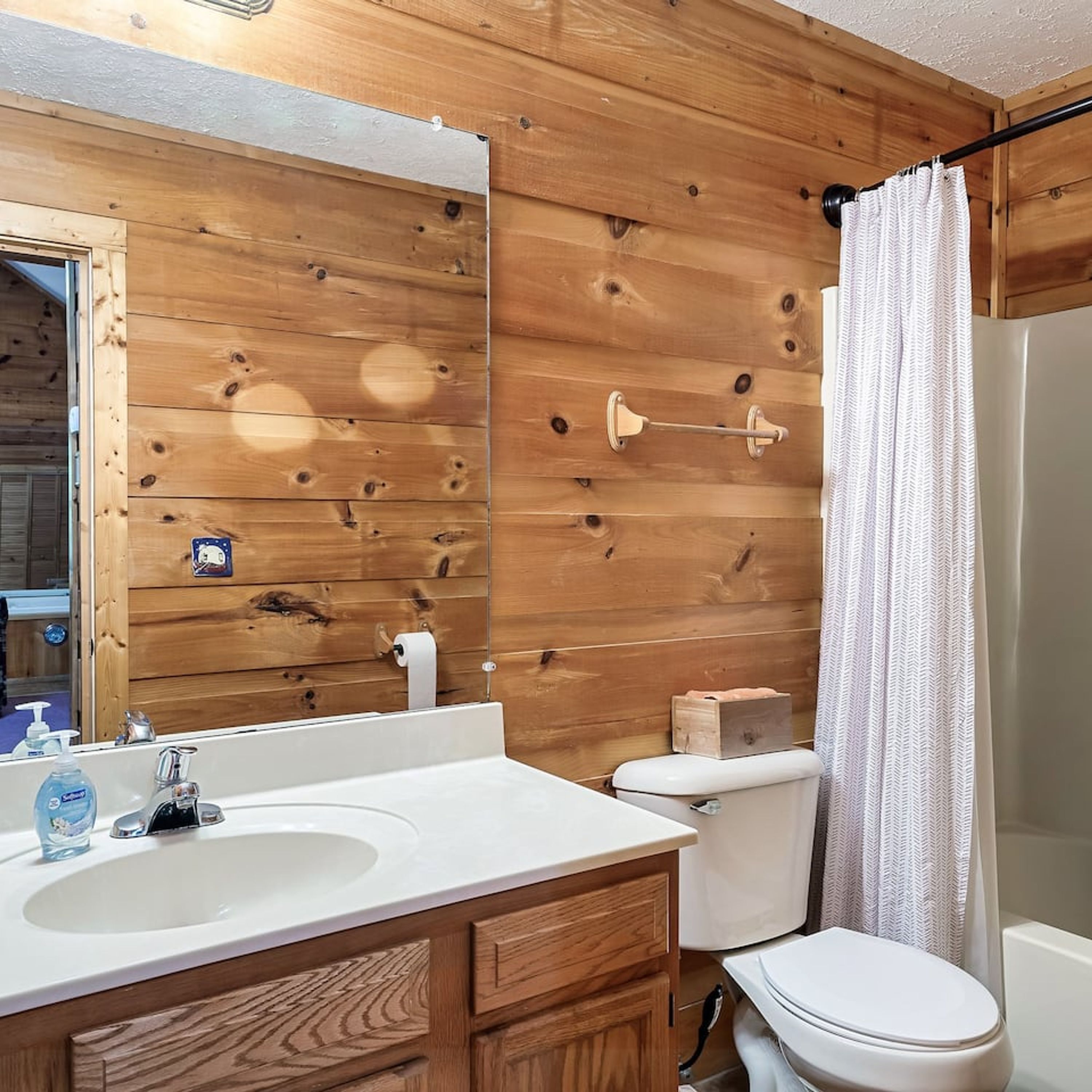 A bathroom with wooden walls, a white sink, and a toilet.