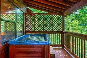 A wooden deck with a hot tub, wooden railings, and a lattice screen.