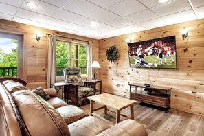 Relax in this inviting living room with a leather sofa, coffee table, and mounted TV.