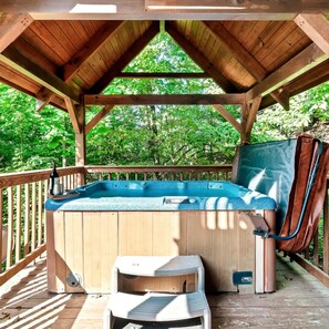 Relax on the elevated deck with a hot tub and seating area overlooking the surrounding greenery.
