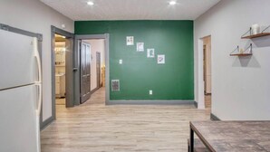 A hallway with a green wall, wooden flooring, and a door leading to a kitchen. - Artistic 1BR - APT - Near Downtown Mass Ave (Indianapolis)