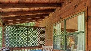 Una terraza de madera con un jacuzzi, dos mecedoras y una celosía.