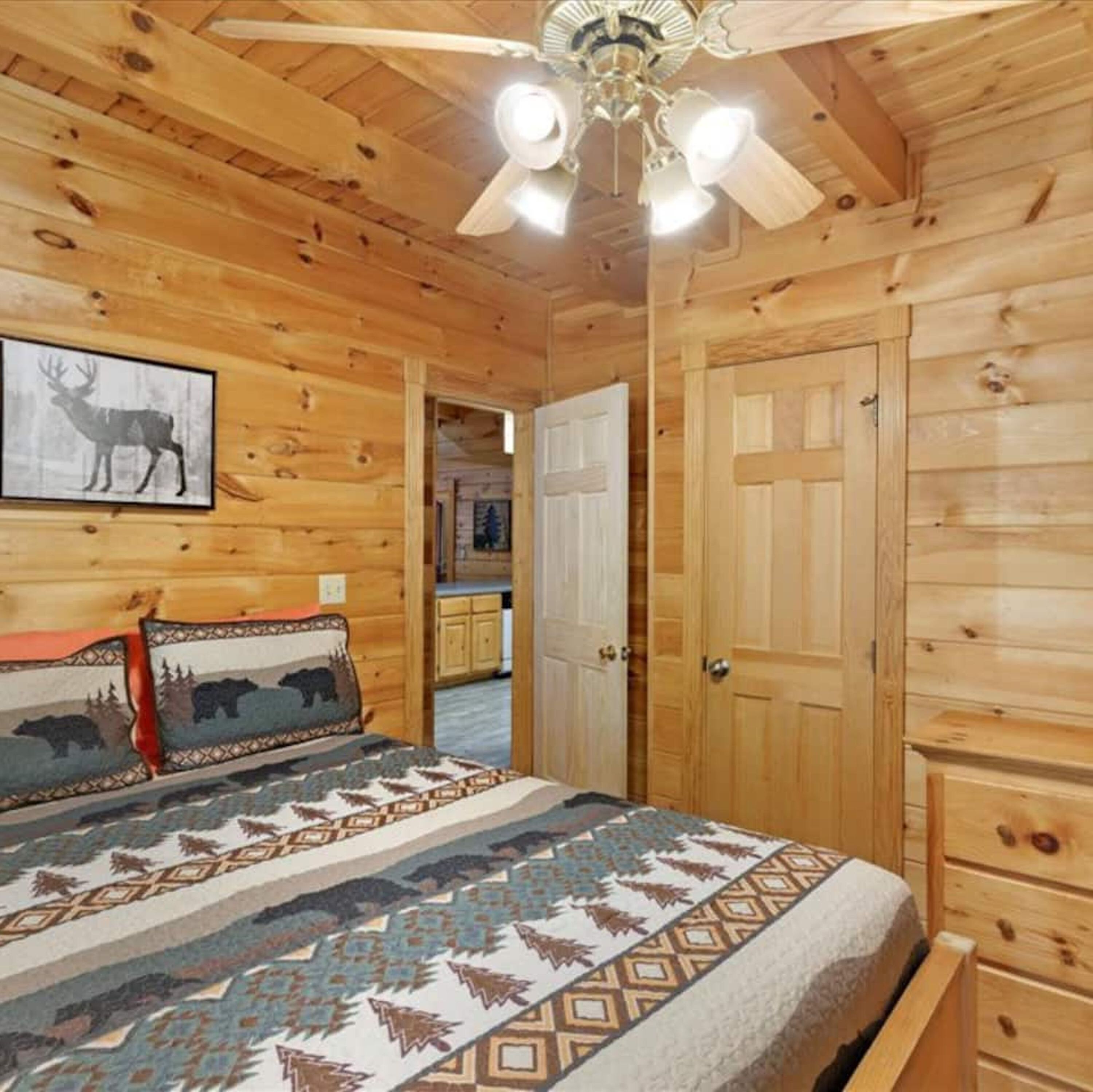 Ein Schlafzimmer einer Holzhütte mit einem Bett, einem Deckenventilator und einem Bild von einem Hirsch.