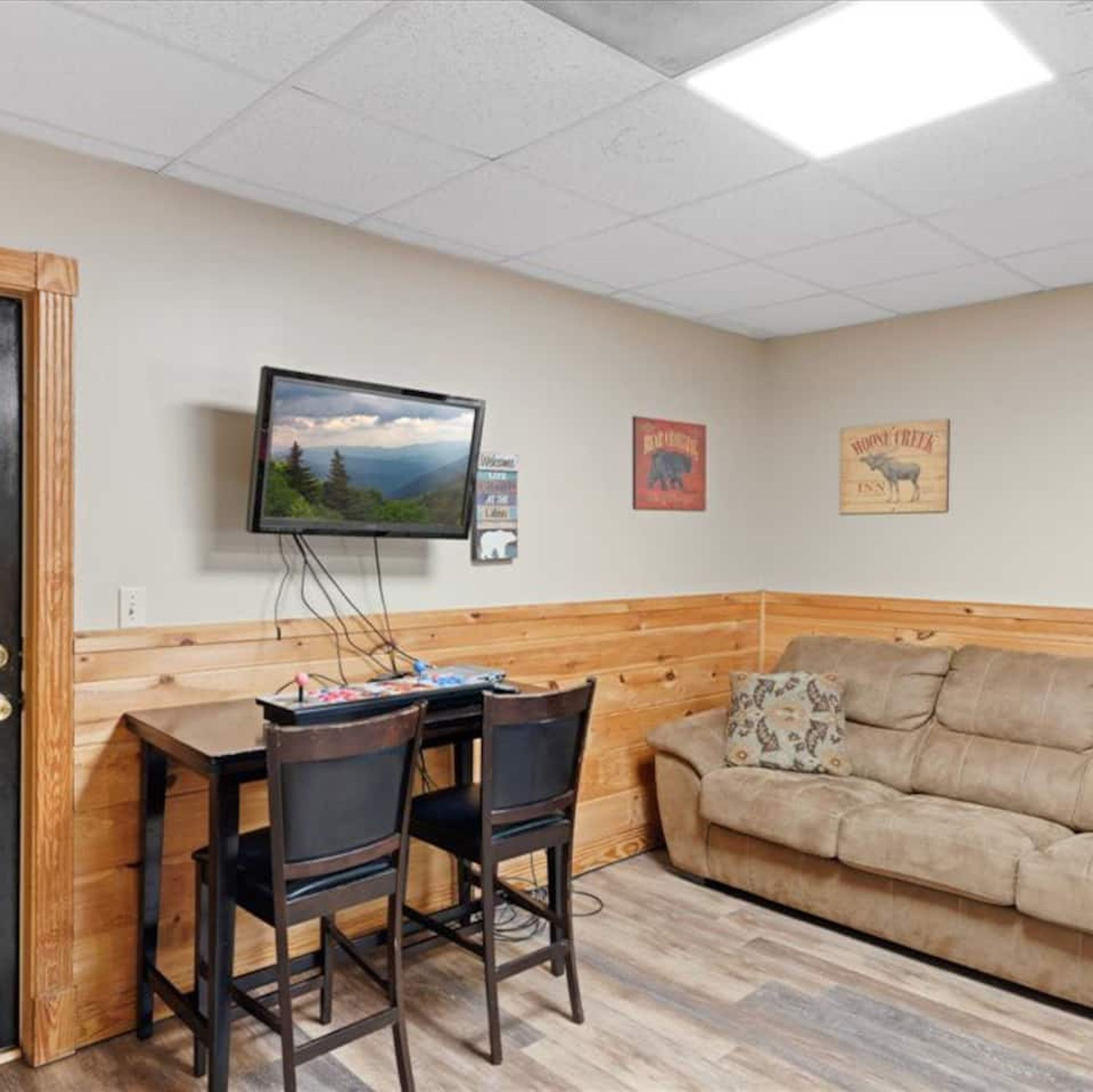 A room with a wooden bench, a sofa, and a TV mounted on the wall.