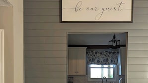 A kitchen with a "be our guest" sign, wooden flooring, and a potted plant. - 180 Degree Seneca Lake Views, privacy galore with hot tub. Sleeps 9
 (Senecaville)