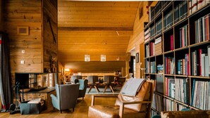 A cozy log cabin interior with a wooden bookshelf, leather armchair, and a dining area. - New in Grindelwald-Chalet Caramelle, Top of Grindelwald (Grindelwald)