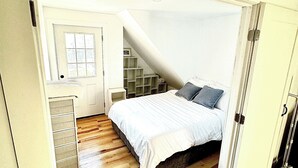 A bedroom with a bed, a dresser, a window, and a door.