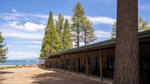 A covered outdoor area with a wooden building, benches, and a view of the ocean. - Camp Richardson Historic Resort (South Lake Tahoe)