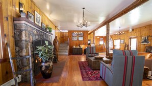 A wooden interior with a stone fireplace, a chandelier, and a staircase leading to a second floor. - Camp Richardson Historic Resort (South Lake Tahoe)