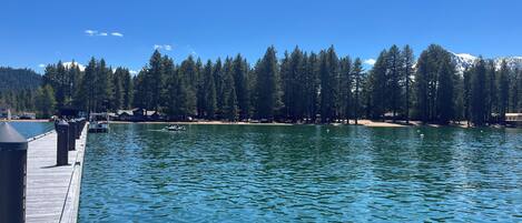 A dock extending into a calm lake with a forested shoreline and a mountain in the background.