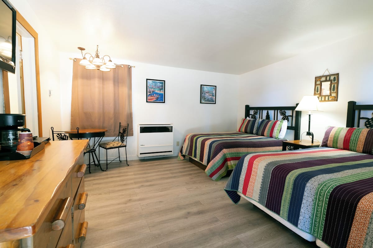 Ein Schlafzimmer mit zwei Betten, einem Holztisch, einem Stuhl, einem Tisch und einer Deckenleuchte.