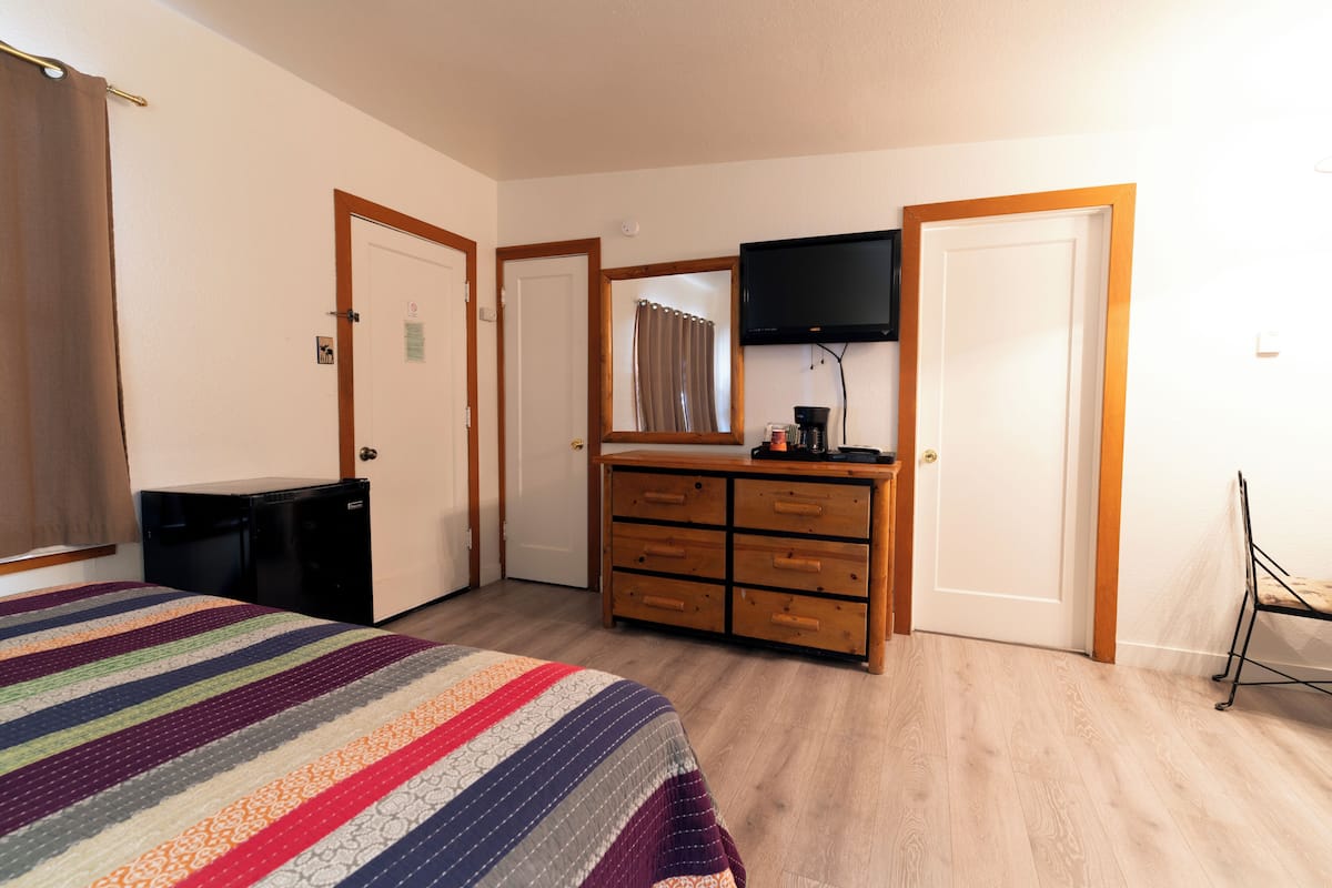 Ein Schlafzimmer mit einem Bett, einem Schminktisch, einem Fernseher und einem Schreibtisch.