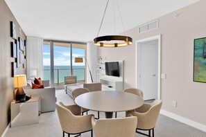 Une chambre d’hôtel moderne avec un balcon, une table à manger ronde et un téléviseur.