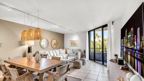 A modern living room with a dining area, featuring a large window with a city view, a sofa set, and a TV on a stand. - Tropical Retreat with Beach & Resort Amenities (Key biscayne)