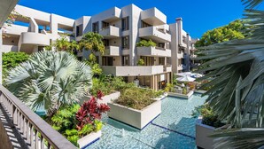 A modern hotel with multiple balconies, a swimming pool, and lush tropical landscaping. - Tropical Retreat with Beach & Resort Amenities (Key biscayne)