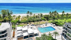 A resort with a swimming pool, beach view, and palm trees. - Tropical Retreat with Beach & Resort Amenities (Key biscayne)