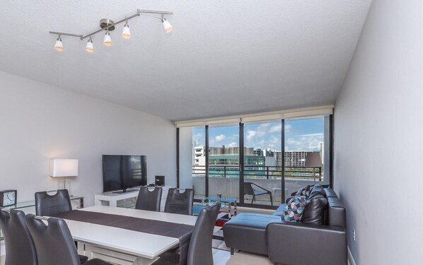 Un salon moderne avec un coin repas, de grandes fenêtres et une vue sur la ville.