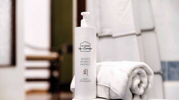 A bathroom with a white bottle labeled "MY HOME in Como" and a rolled white towel on a counter.
