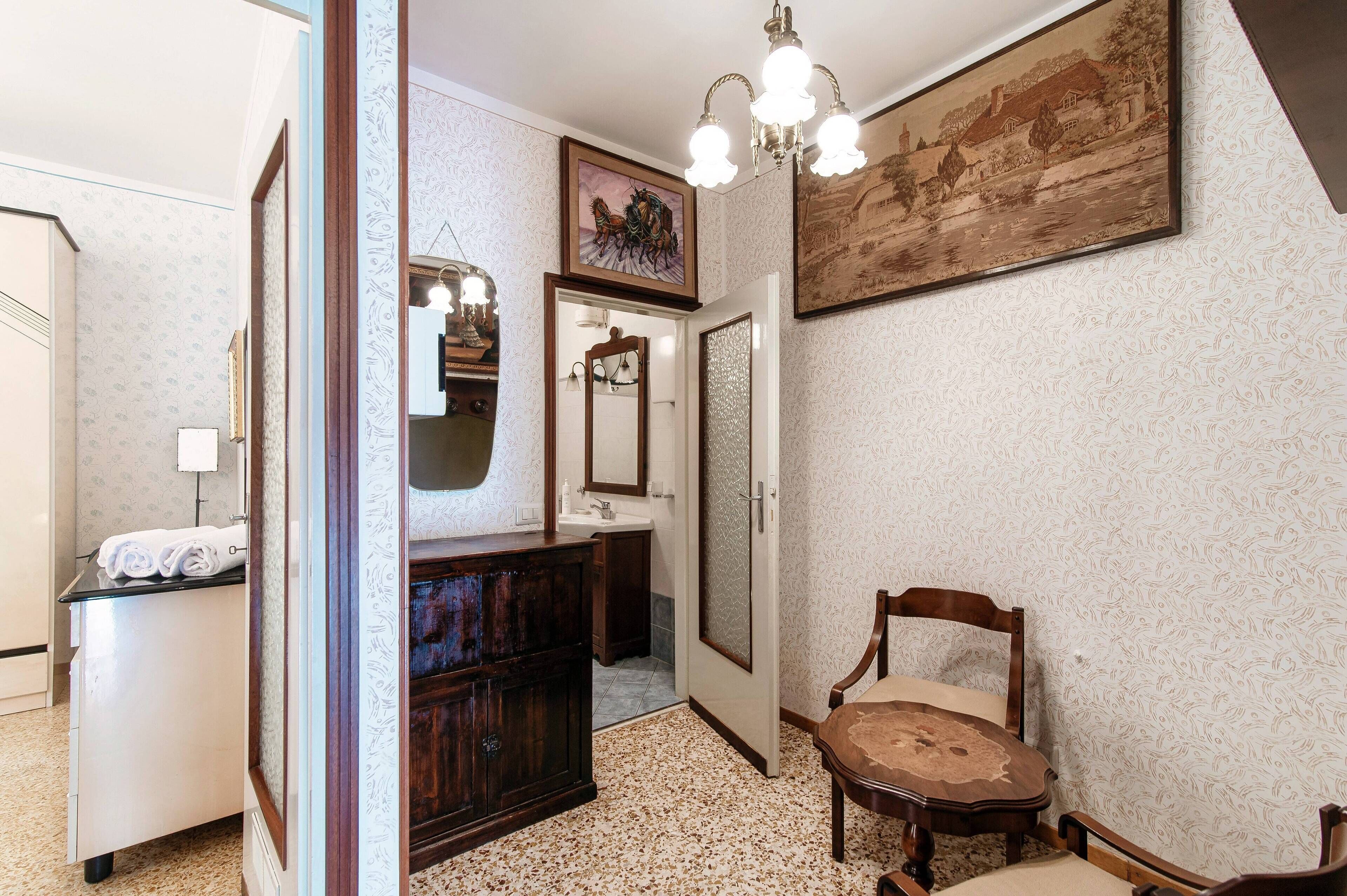 A bathroom with a vanity, mirror, and a chair.