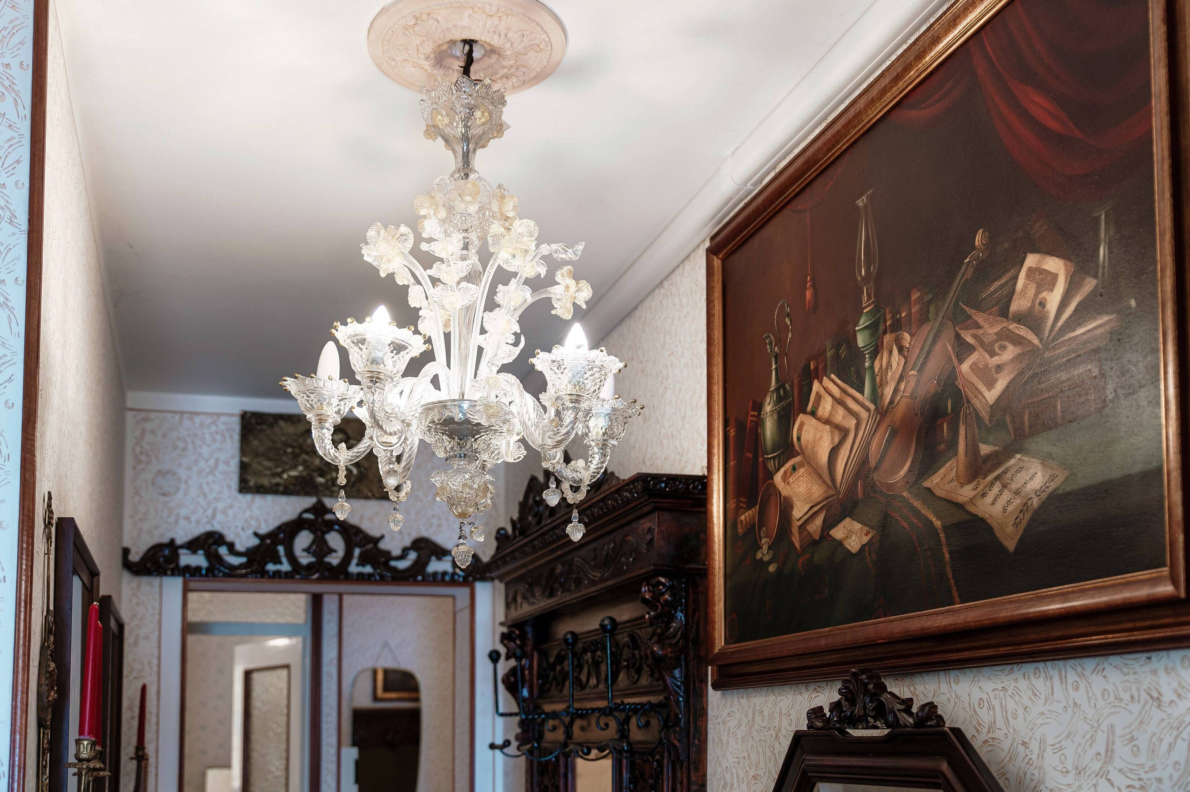 Un candelabro, un cuadro enmarco y muebles ornamentados en una habitación.