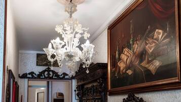 Un candelabro, un cuadro enmarco y muebles ornamentados en una habitación.