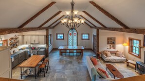 Un loft spacieux avec des poutres apparentes, une grande table à manger, un coin salon confortable et un vitrail.
