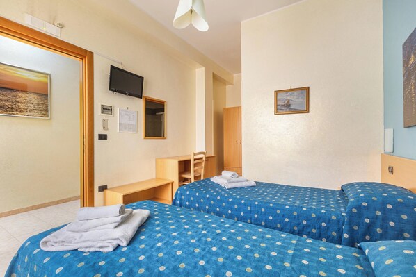 A hotel room with two beds, a desk, and a TV.