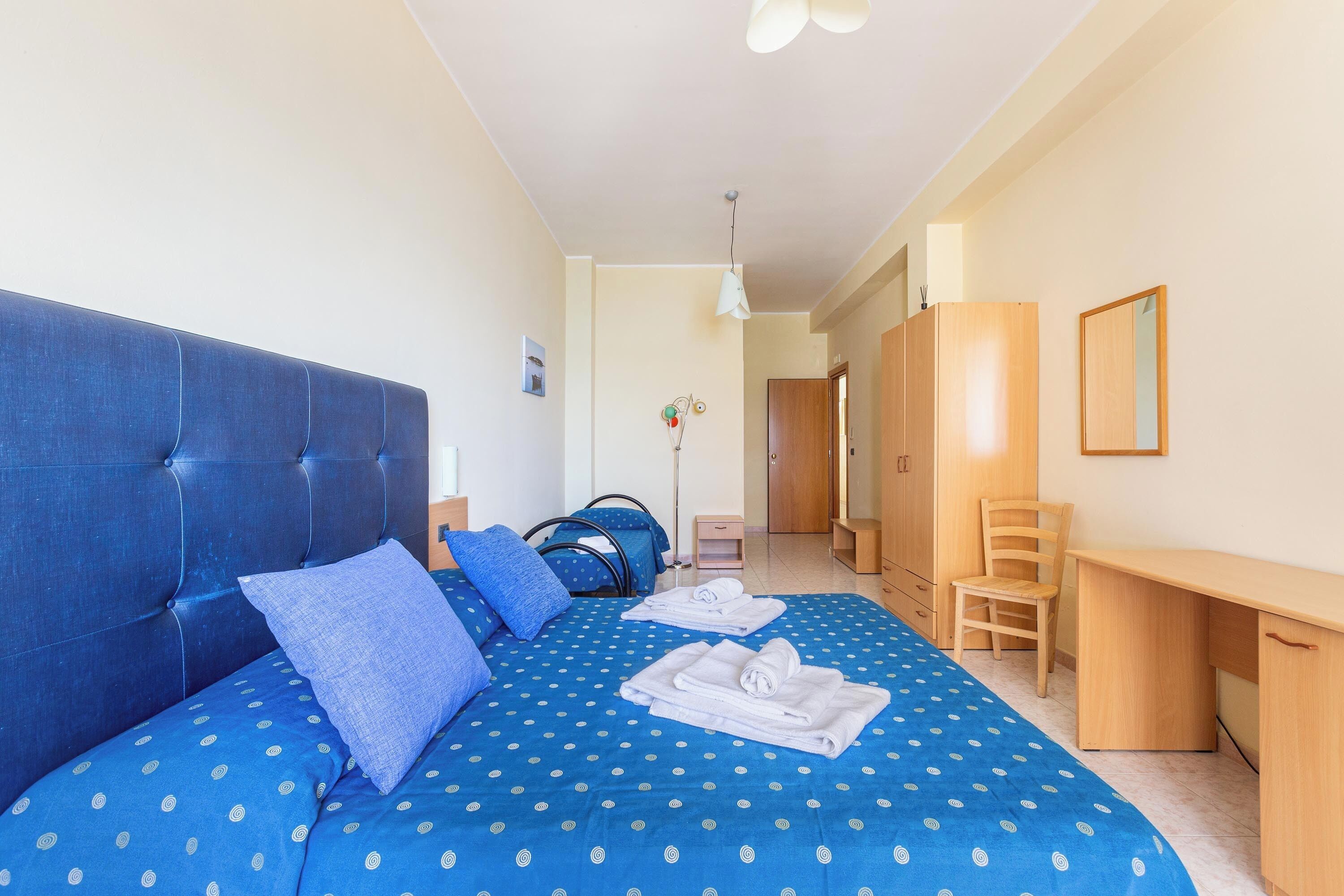 Un dormitorio con una cama grande, un escritorio y una silla.