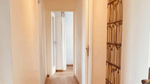 Un pasillo con suelo de madera, paredes blancas y una puerta con diseño decorativo.