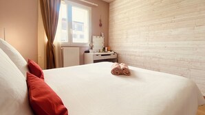 Un dormitorio con cama, tocador con espejo y ventana con cortinas.