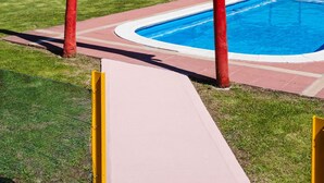 A swimming pool with a red pergola structure, surrounded by a grassy area and a wooden fence. - El Molino del Cidacos (Arnedillo)
