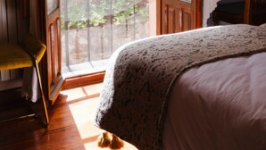A bedroom with a large window, a bed, a chair, and a nightstand. - El Molino del Cidacos (Arnedillo)