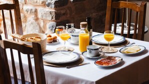 A breakfast table set with plates, glasses, and a basket of pastries. - El Molino del Cidacos (Arnedillo)