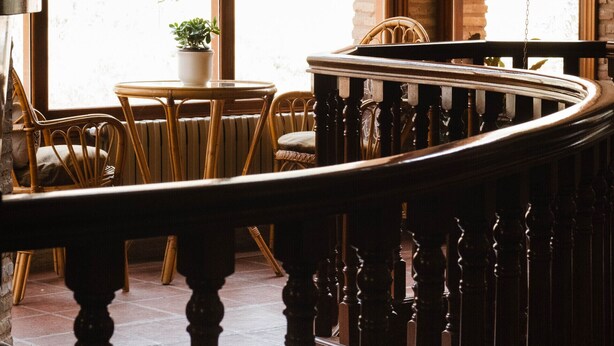 A wooden staircase with a railing, leading to a seating area with chairs and a table. - El Molino del Cidacos (Arnedillo)
