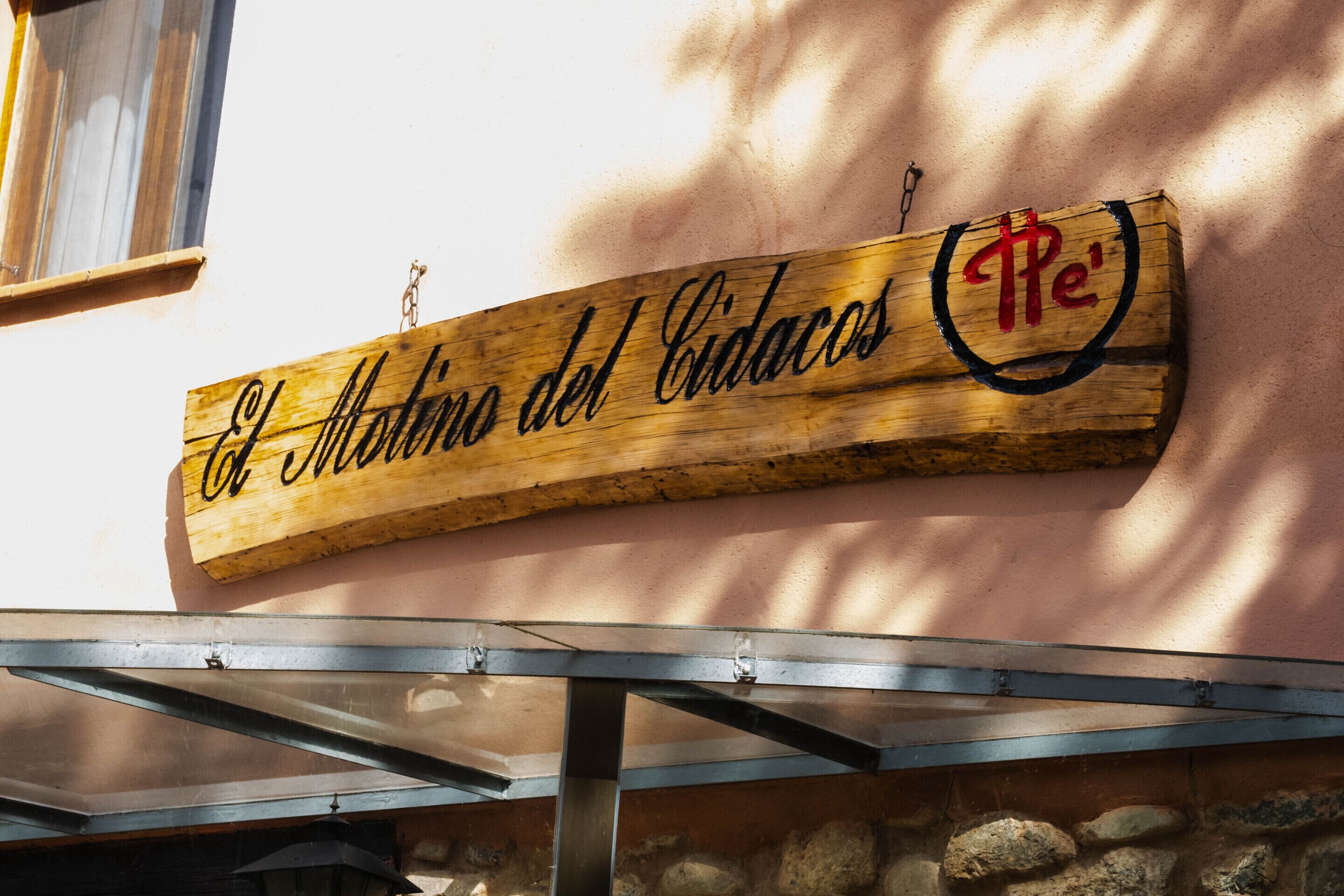 Un letrero de madera con el texto 'El Molino del Cidacos' y un logotipo con la letra 'P' en un círculo.
