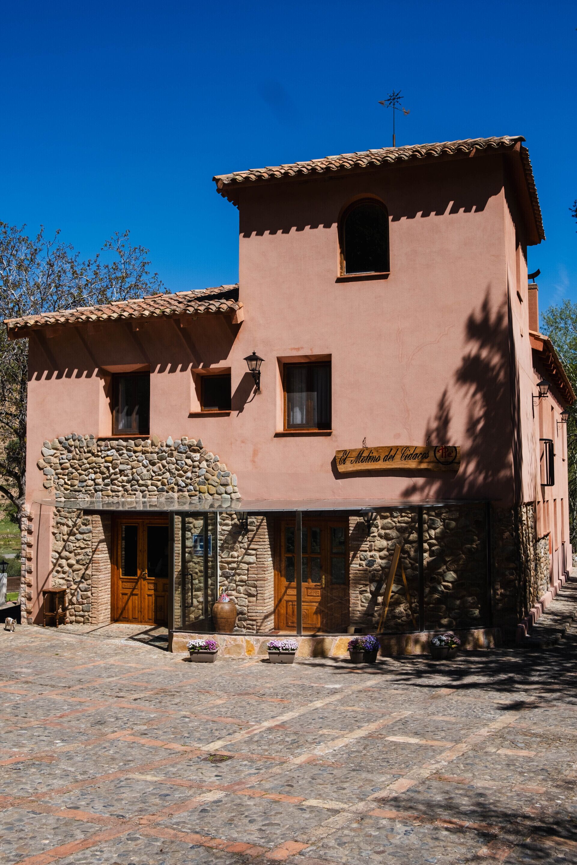 Un edificio de dos pisos con fachada de piedra, puertas de madera y un letrero que dice 'El Matin del Vino'.