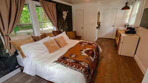Une chambre avec un lit, un petit coin cuisine et un ventilateur de plafond.