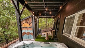 Un bain à remous doté de plusieurs jets, entouré d’une terrasse en bois et d’un espace couvert agrémenté de guirlandes lumineuses.