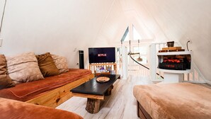 Un salon chaleureux avec un banc en bois, un canapé et un téléviseur.