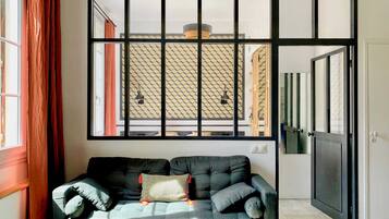 A modern living room with a sofa, a patterned wall, and a large window.